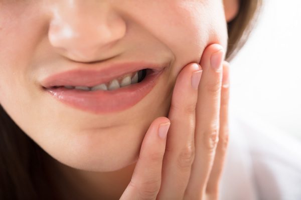 Woman holding cheek with tooth pain