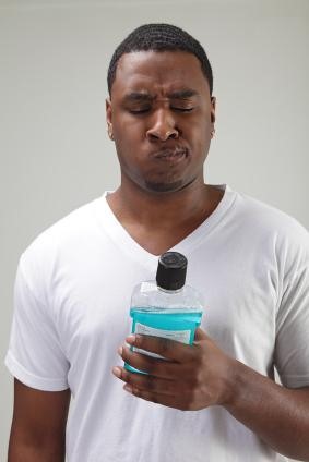 Man rinsing with mouthwash reading the label